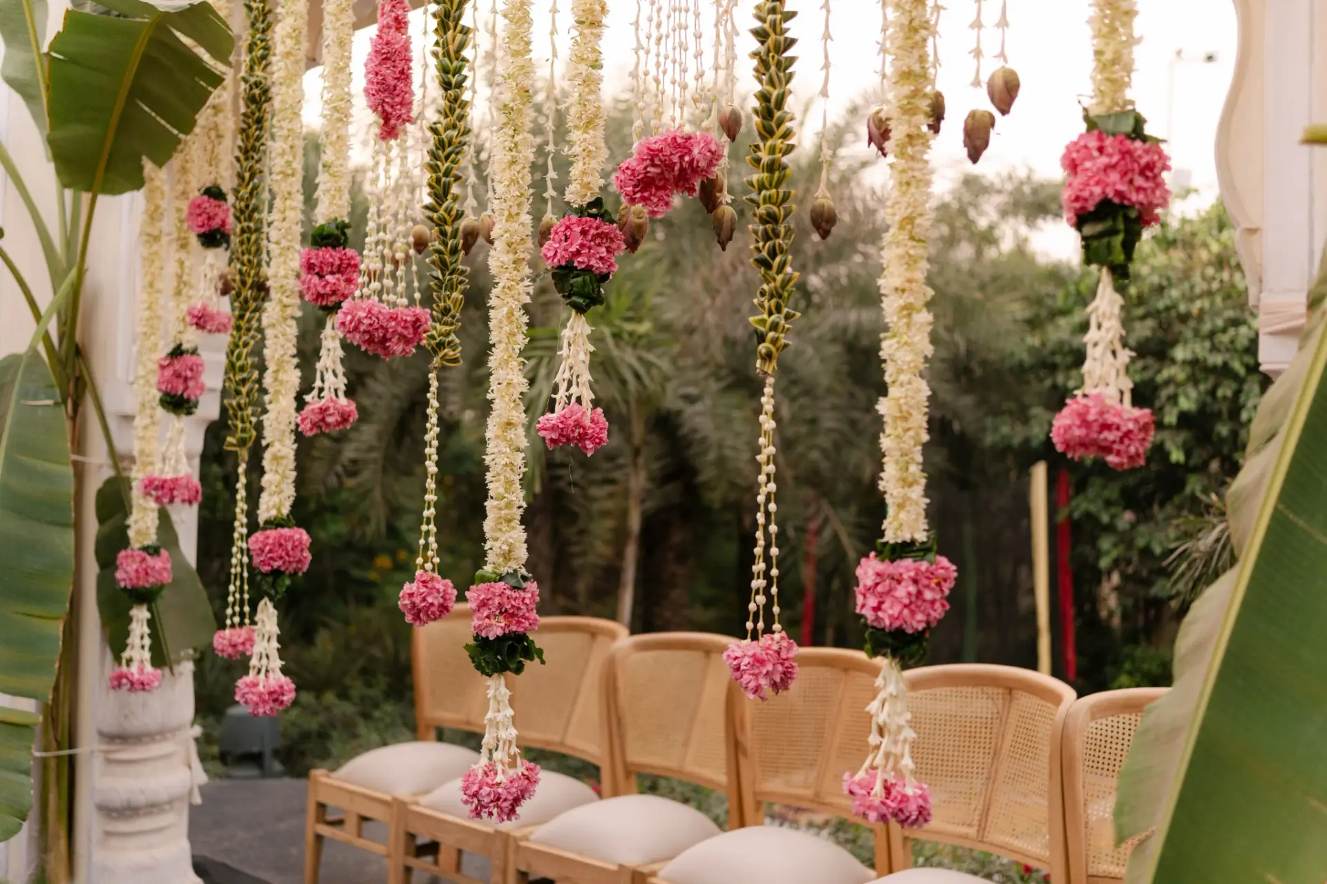 Wooden ceremony chairs beneath pink and white floral hangings at Hyatt Regency Jaipur Mansarovar, Jaipur