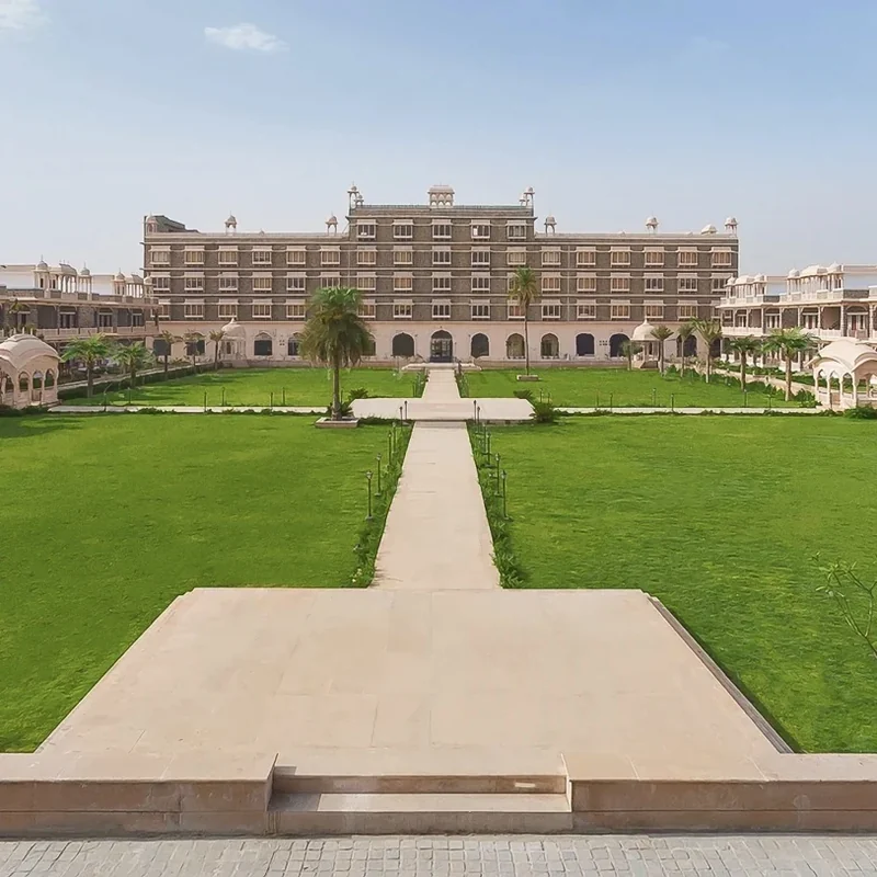 Palatial hotel overlooking a broad lawn and central pathway at Bhanwar Singh Palace.