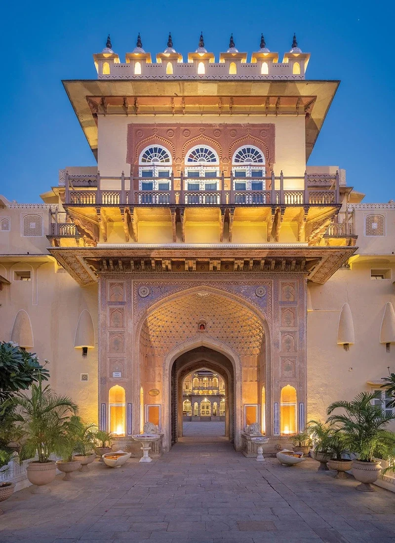 Front entrance façade and ornate balcony at Chomu Palace in evening light.