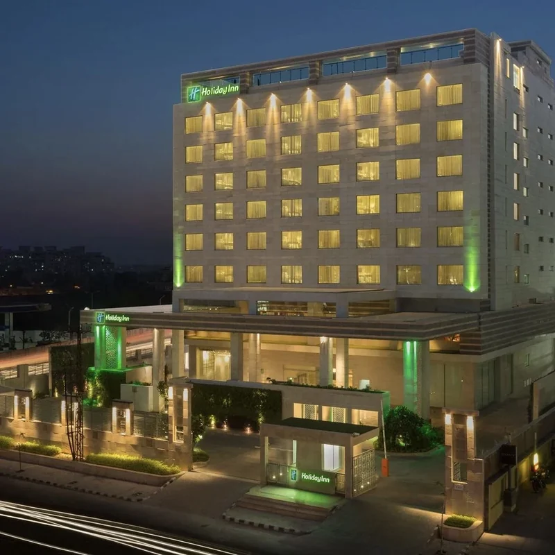 Hotel façade and illuminated entrance after dark at Holiday Inn Jaipur City Centre.