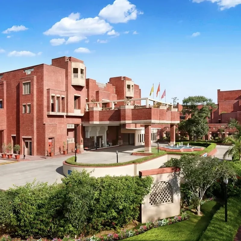 Terracotta-coloured hotel buildings and landscaped courtyard at ITC Rajputana.