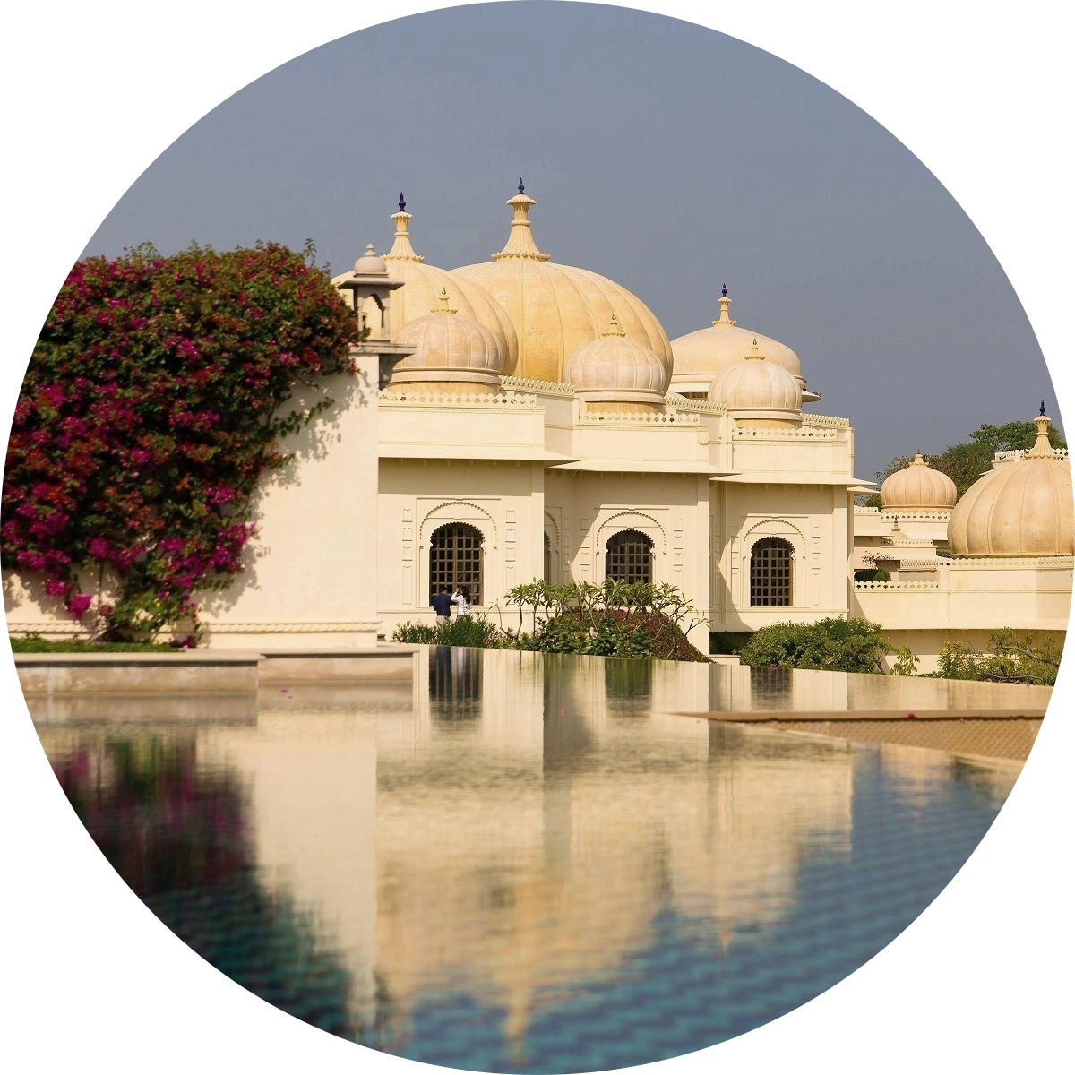 The majestic traditional domes of The Oberoi Udaivilas in Udaipur, India, reflecting clearly in a luxury resort swimming pool.