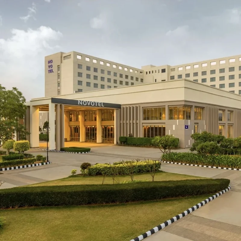 Hotel entrance, landscaped driveway and modern façade at Novotel Jaipur Convention Centre.