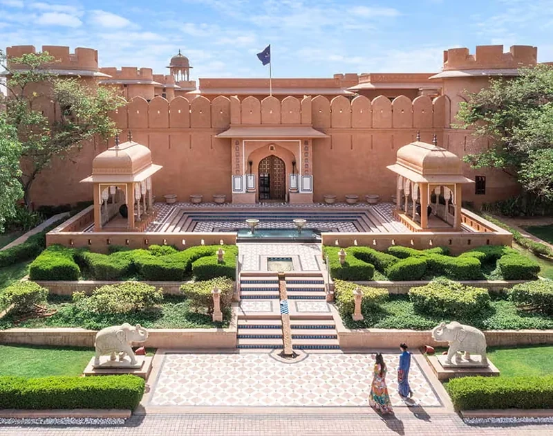 Formal garden, elephant sculptures and centered sandstone entrance at The Oberoi Rajvilas.