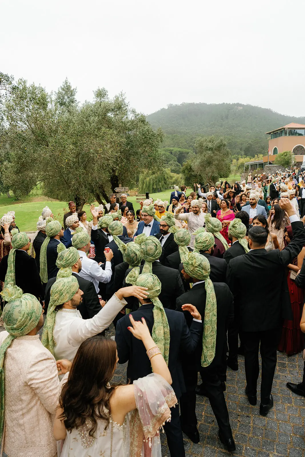 Family and guests dancing in pale green safas during the baraat