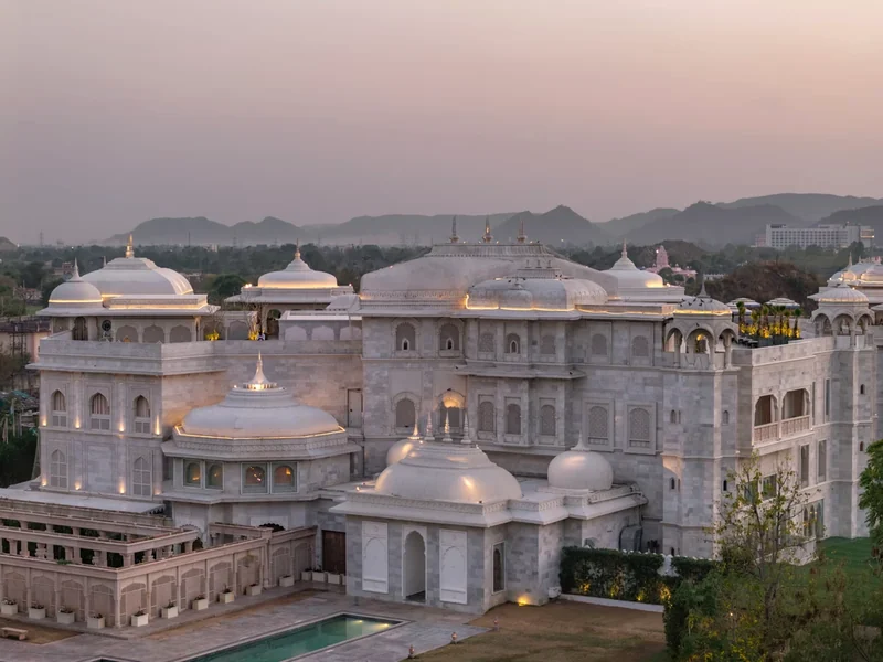 White palace façades and domes against the hills at dusk at Raffles Jaipur.