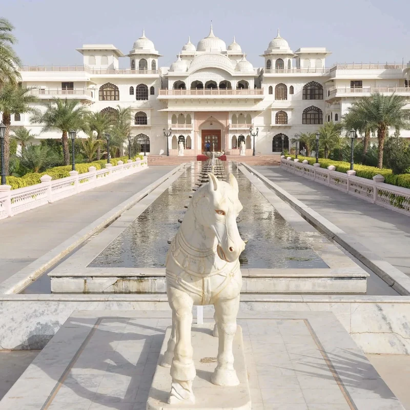 White palace façade and long reflecting pool with sculpted horses at Shiv Vilas Resort.