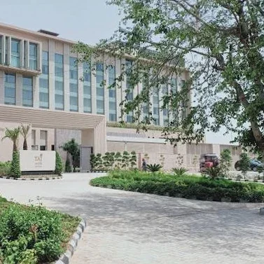 Hotel façade and landscaped arrival driveway in daylight at Taj Amer.